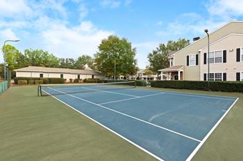 Blue tennis court with houses in the background